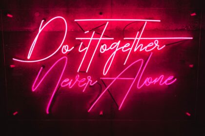 Pink neon on a black background. Text reads, "Do it together, never alone."