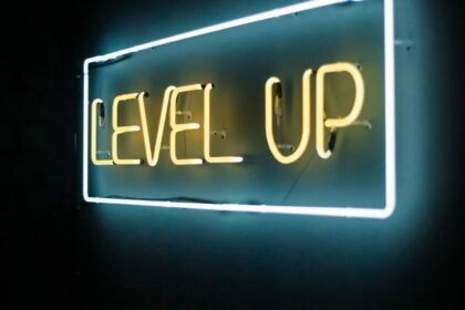 yellow and white neon text reads "level up" on a brick wall